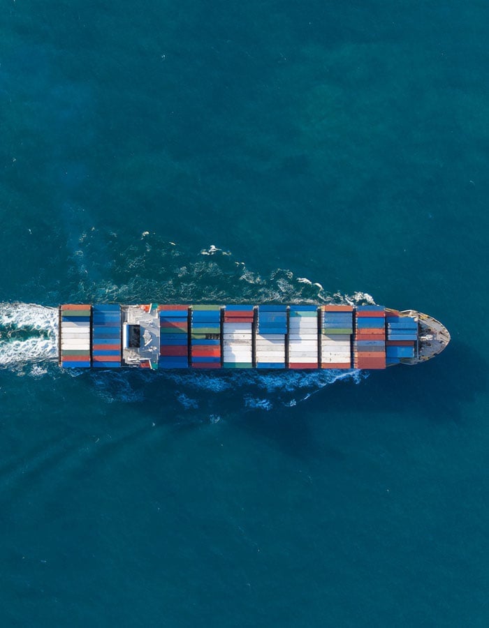 Aerial view of a cargo ship traveling through deep blue ocean waters.