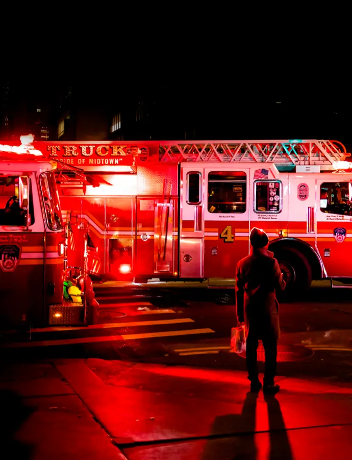 Emergency vehicles with lights on in a dark setting, illuminating an emergency responder